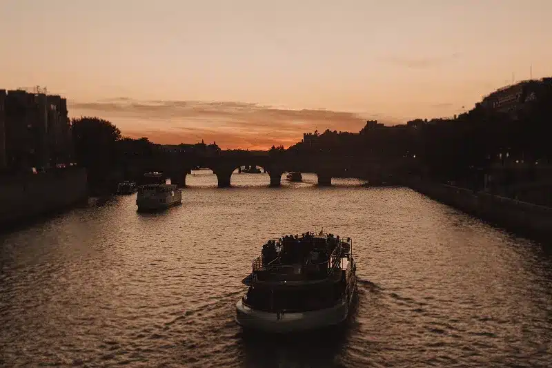 A Group and Private Europe Tour Packages on a boat on a river with a bridge in the background 