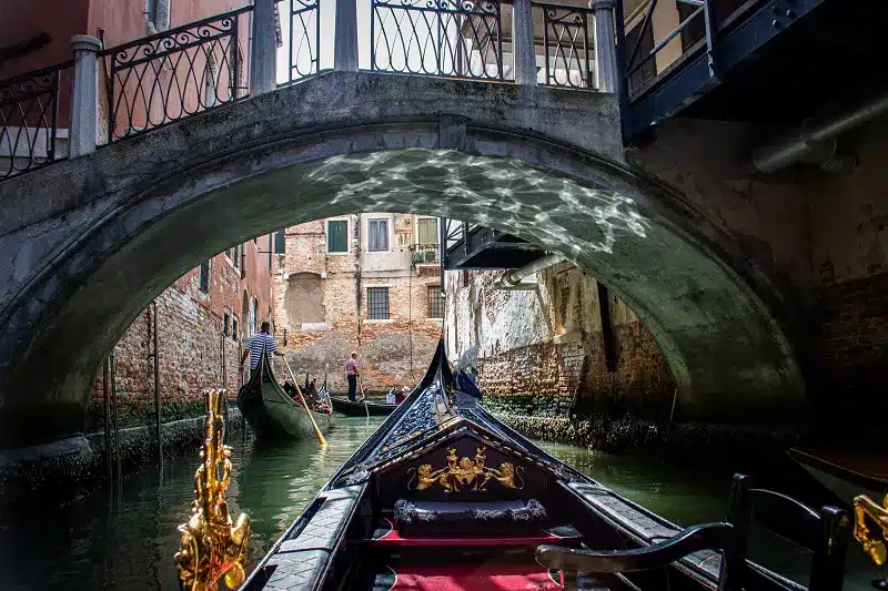 a gondola on a canal under a bridge on guided Europe tour packages