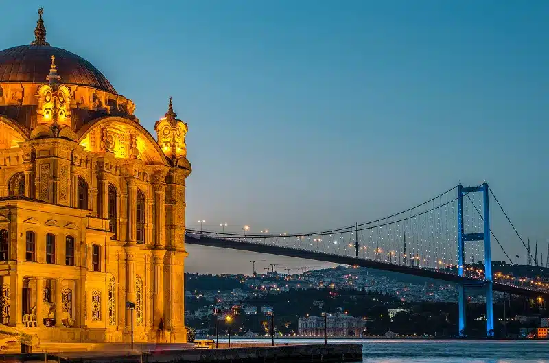 a bridge over water with a building and a city in the background with our Best Things to Do in Istanbul