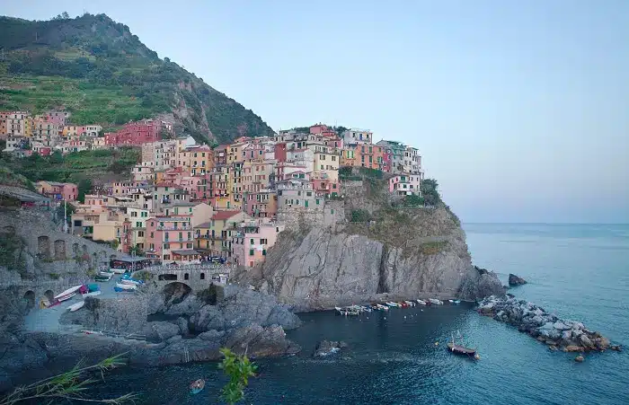 a bunch of house and boats on the edge of a mountain in Cinque Terre which is one of the best places to visit in Italy