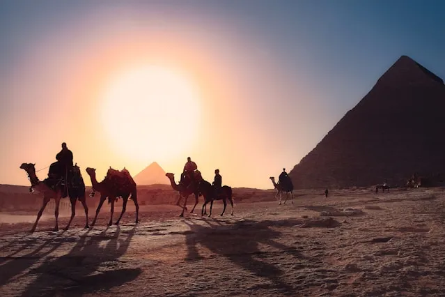 A Group of Tourists Riding Camels while your Tours of Egypt