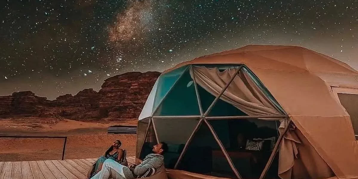 Two people comfortably sitting in a tent, enjoying the peacefulness of a star-filled sky during a camping experience. while their Jordan itinerary 6 days