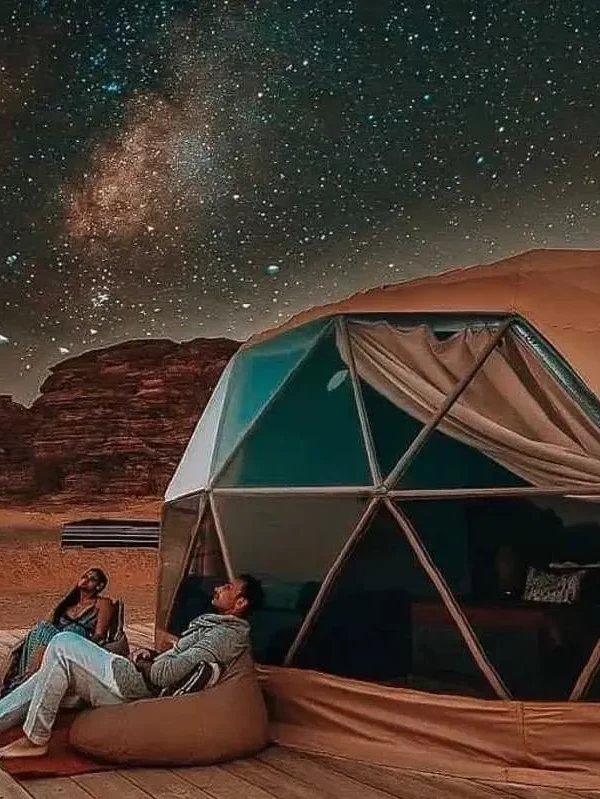 Two people comfortably sitting in a tent, enjoying the peacefulness of a star-filled sky during a camping experience. while their Jordan itinerary 6 days