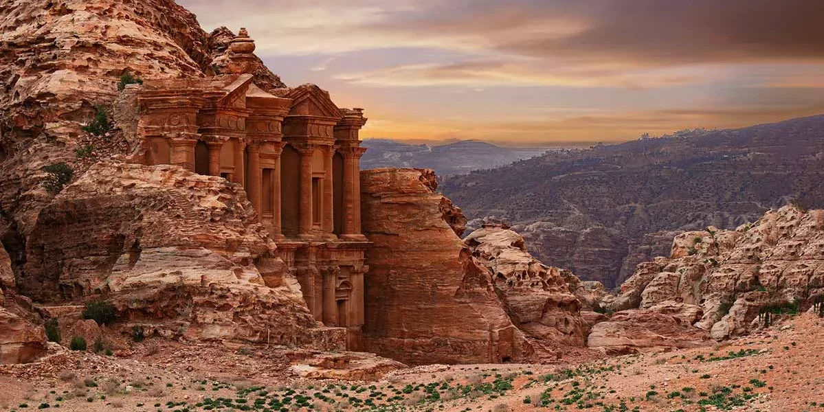 Monastery in Petra, Jordan, showcasing its grand facade carved into rock amidst a desert landscape. in our Jordan itinerary 10 days