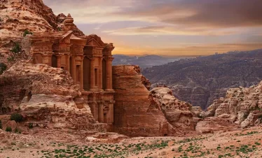 Monastery in Petra, Jordan, showcasing its grand facade carved into rock amidst a desert landscape. in our Jordan itinerary 10 days