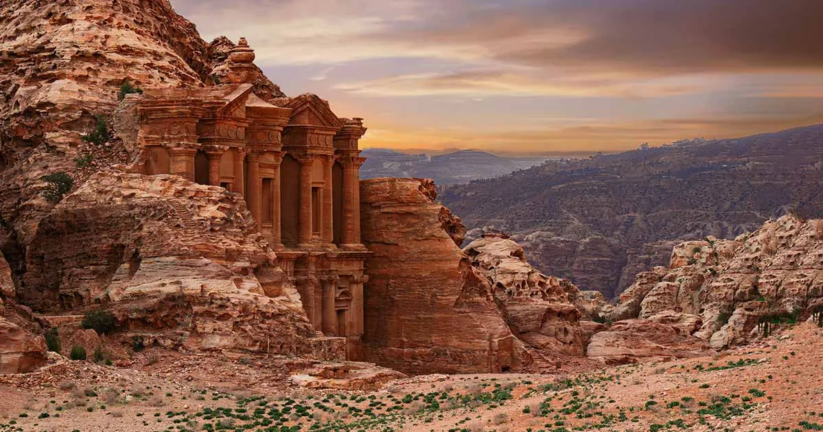 Monastery in Petra, Jordan, showcasing its grand facade carved into rock amidst a desert landscape. in our Jordan itinerary 10 days