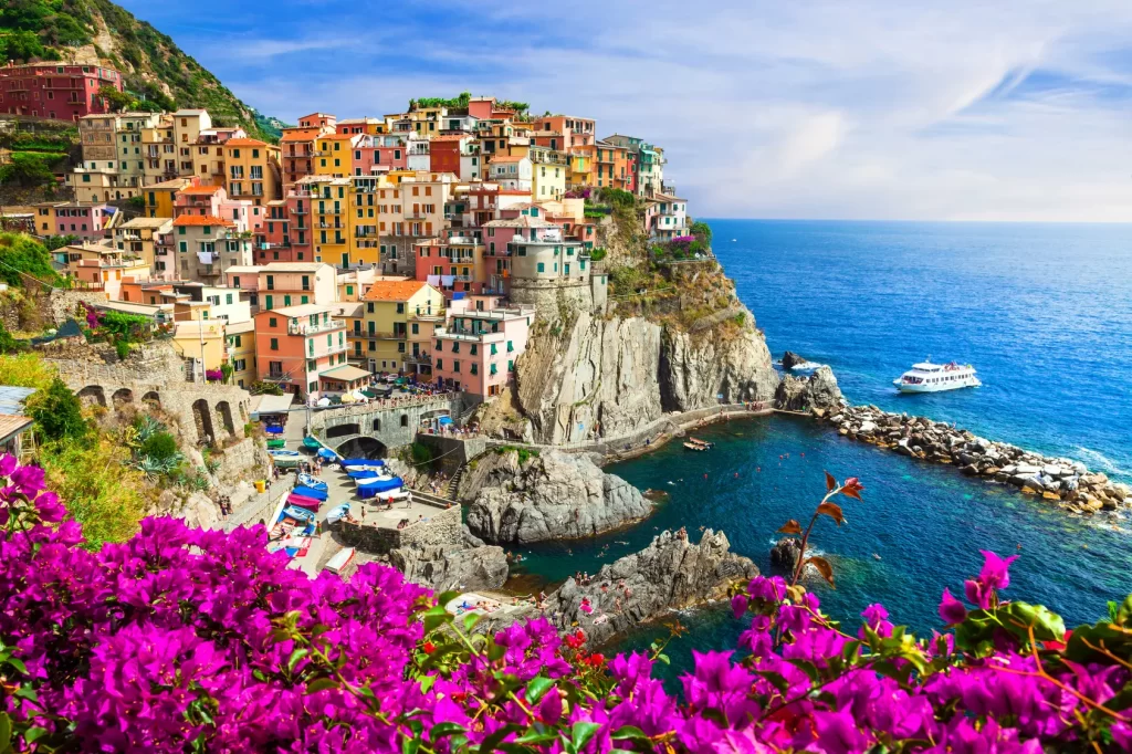 A picturesque Italian coastal village adorned with vibrant flowers, showcasing its natural beauty and charm while our Italy Itinerary 15 days