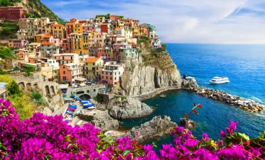 A picturesque Italian coastal village adorned with vibrant flowers, showcasing its natural beauty and charm while our Italy Itinerary 15 days