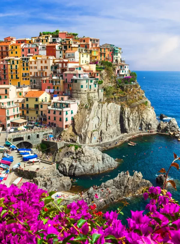 A picturesque Italian coastal village adorned with vibrant flowers, showcasing its natural beauty and charm while our Italy Itinerary 15 days