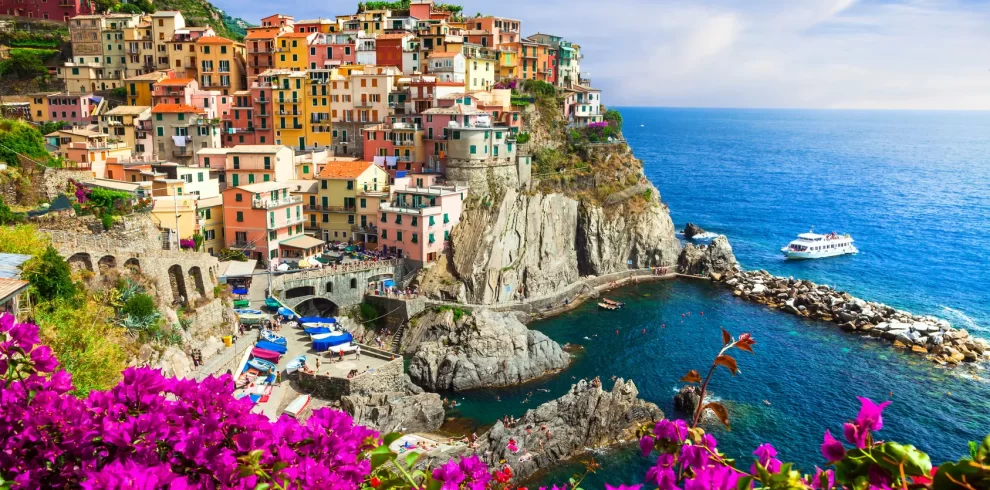 A picturesque Italian coastal village adorned with vibrant flowers, showcasing its natural beauty and charm while our Italy Itinerary 15 days