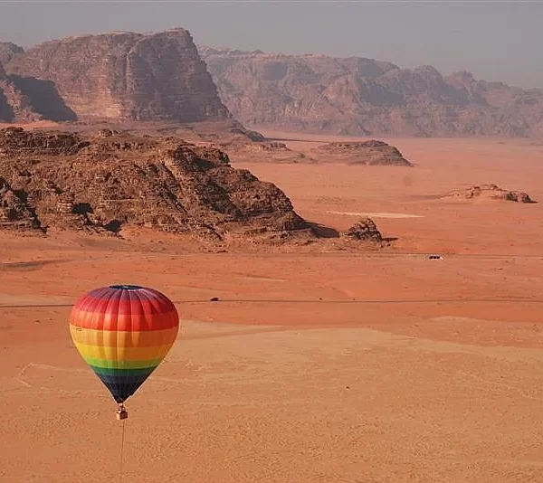 1. A vibrant hot air balloon soars above the vast desert landscape, showcasing the beauty of the arid terrain below while our Jordan itinerary 8 days