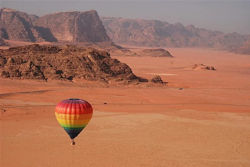 1. A vibrant hot air balloon soars above the vast desert landscape, showcasing the beauty of the arid terrain below while our Jordan itinerary 8 days