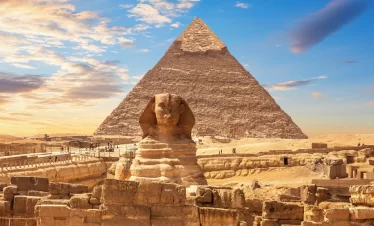 The Great Sphinx and the Pyramid of Giza silhouetted against a vibrant sunset sky with our Egypt itinerary 8 days