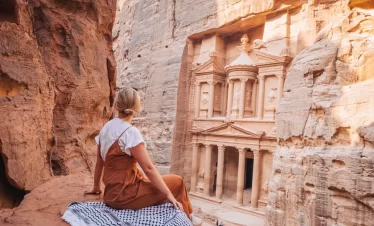A woman tourist is sitting by Petra, Jordan: an ancient city known for its rock-cut architecture and water conduit system, showcasing stunning historical significance in our Jordan itinerary 10 days