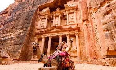 A camel rests at the entrance of Petra's Treasury, showcasing the ancient architecture and desert landscape in Jordan itinerary 5 days