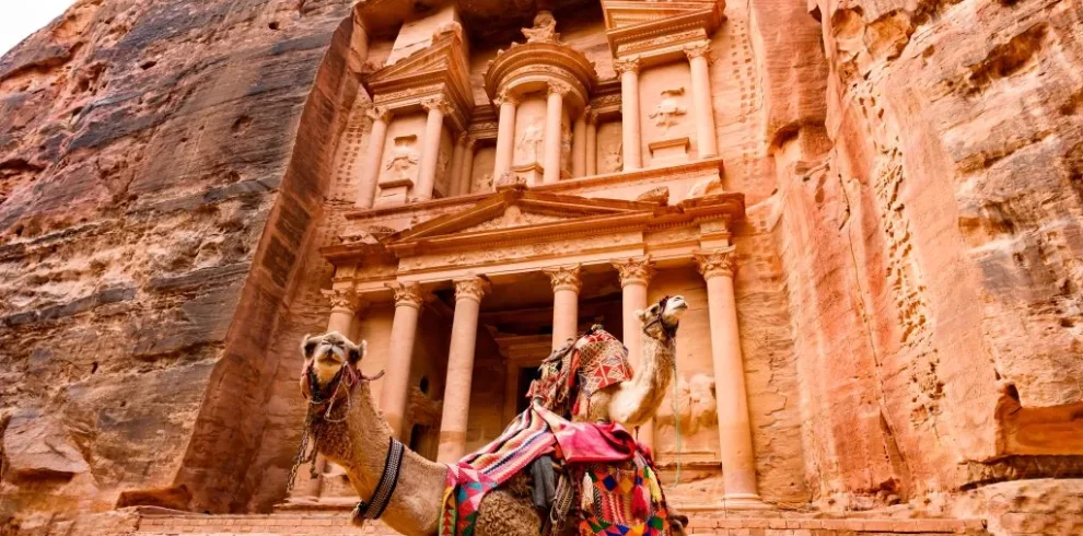 A camel rests at the entrance of Petra's Treasury, showcasing the ancient architecture and desert landscape in Jordan itinerary 7 days